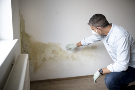 Man in front of wall with mold.